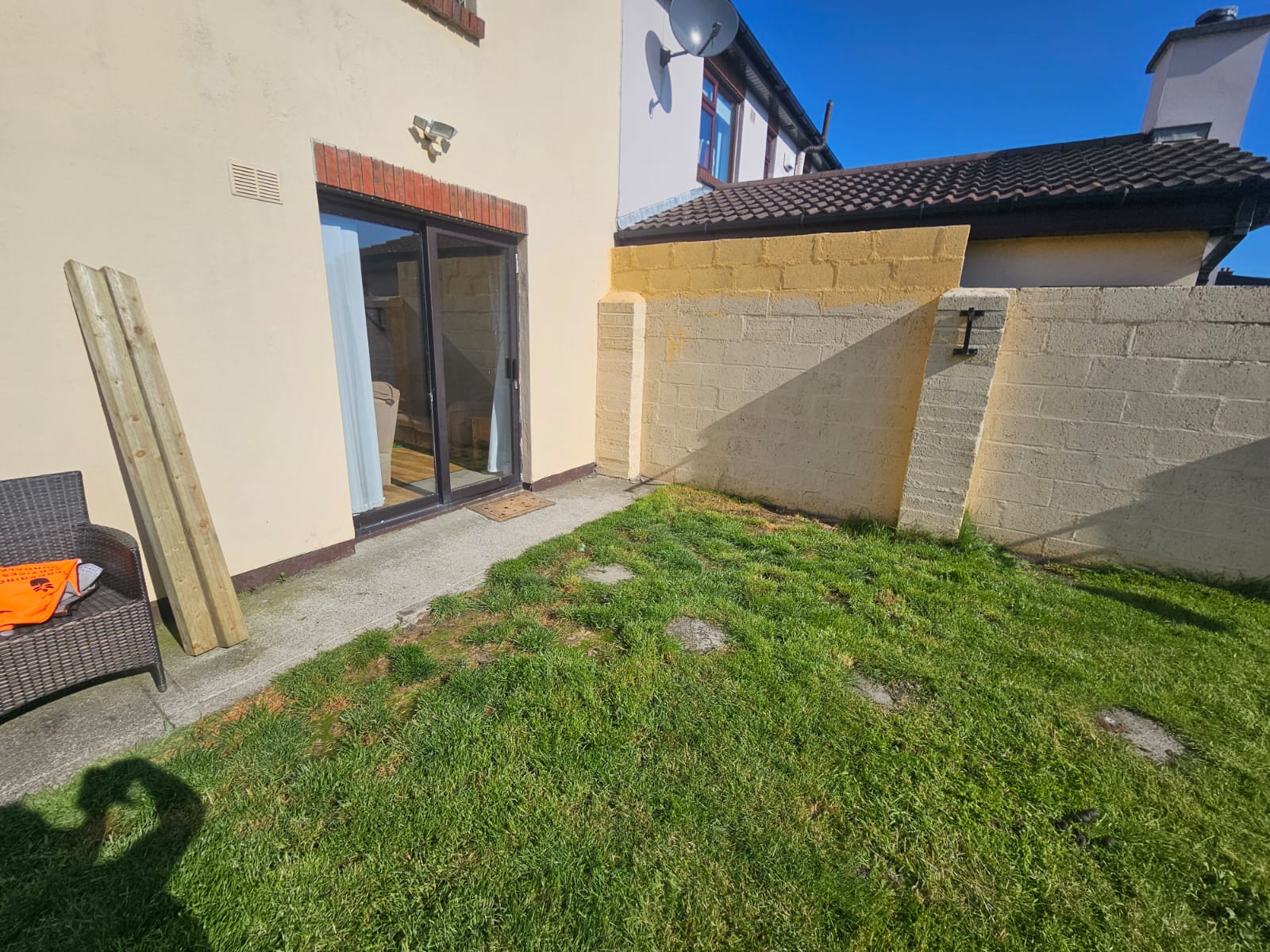 Before photo showing patchy grass patio area with uneven surfaces