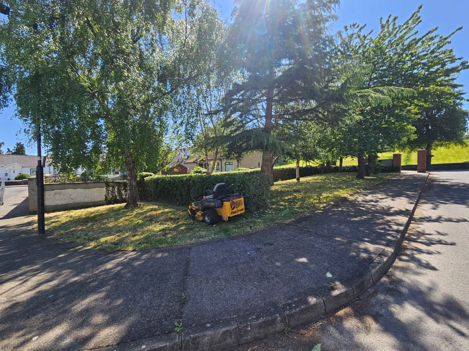 Professional maintenance complete showing immaculate lawn and trimmed hedge